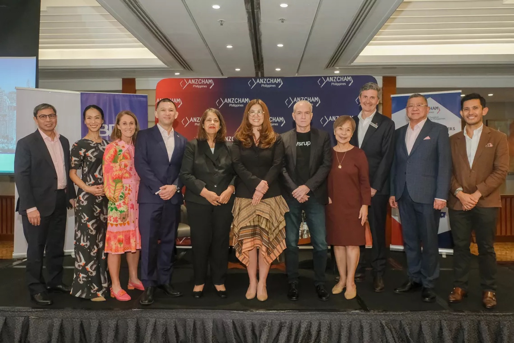 Eleven speakers and guests standing in a line on stage in front of an ANZCHAM Philippines step-and-repeat banner